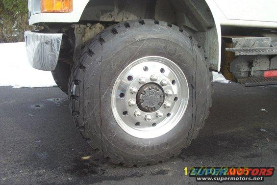 Truck wheel with chrome hubcap and large tire on asphalt