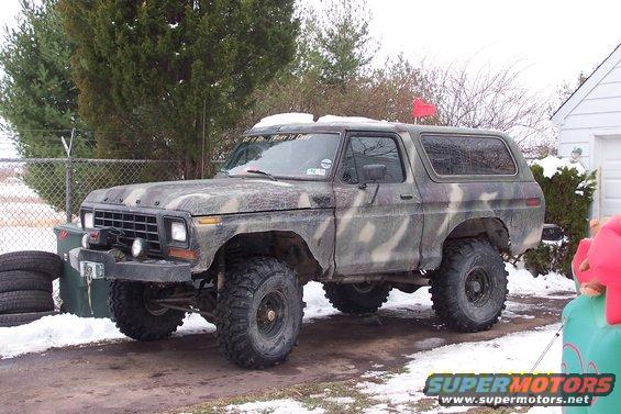Camouflaged 1978 Ford Bronco parked in snowy driveway. Winch mounted on front bumper