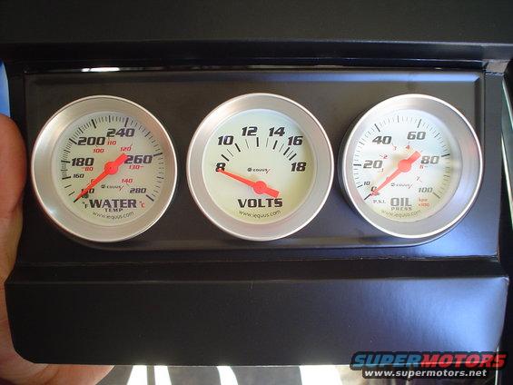 Dashboard gauges for water temp, volts, and oil pressure mounted in a black panel