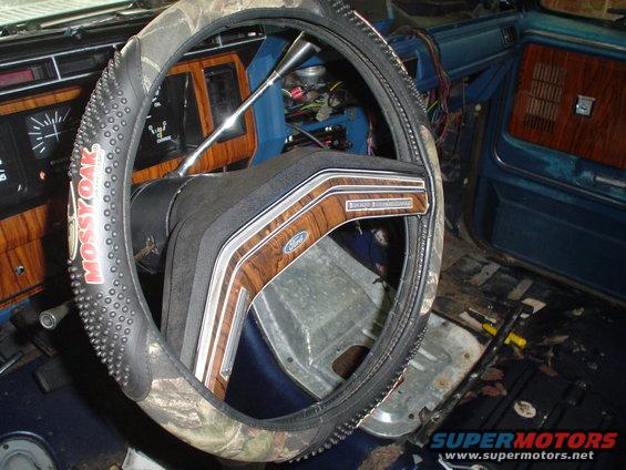 1984 Ford Bronco interior with wood grain trim on the steering wheel and dashboard, and a Mossy Oak steering wheel cover