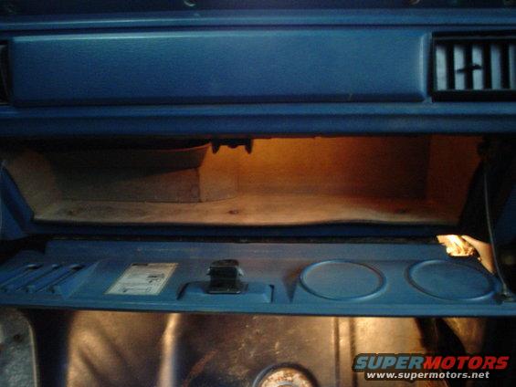 1984 Ford Bronco glove box open, showing interior and light. Some text visible on a label