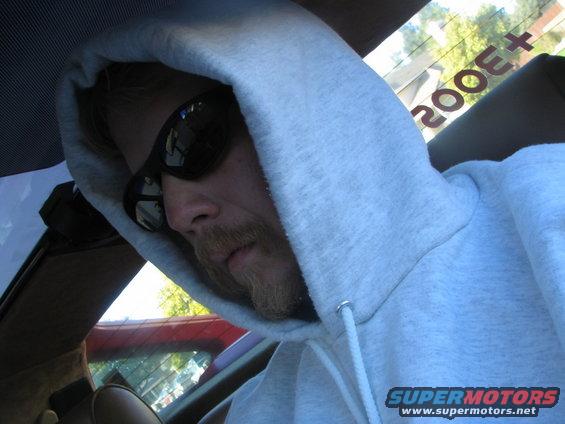 Interior view of a 1986 Pontiac Fiero with a person wearing a hoodie and sunglasses