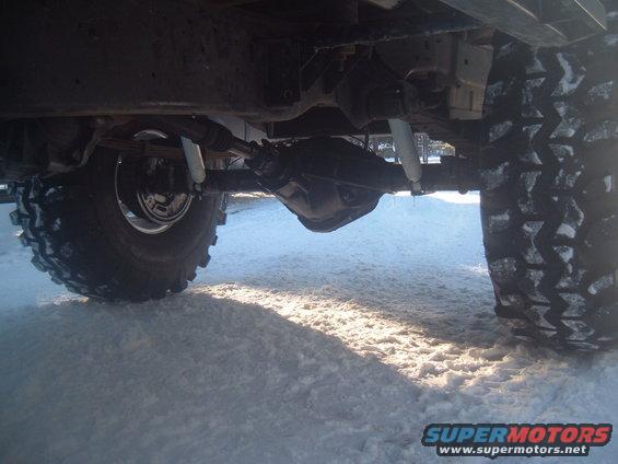 Undercarriage view of a vehicle with large tires in snow