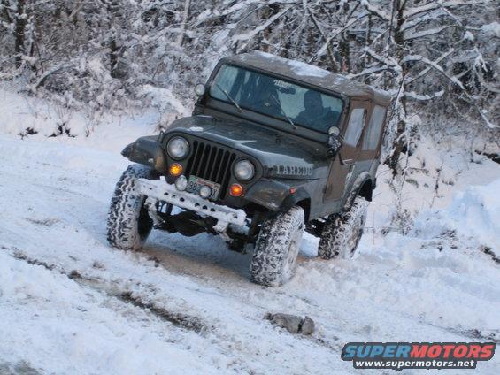 Dark green Jeep CJ-7 Laredo with soft top driving in snow