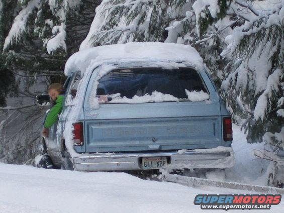 Light blue SUV stuck in snow, kid looking out window. License plate 611-NBP