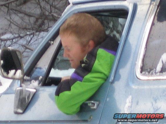 1990 Ford Bronco side view with man in green jacket leaning out window in snow