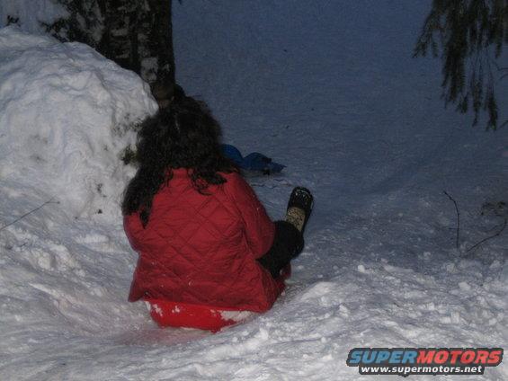 Person in red jacket on red sled in snow