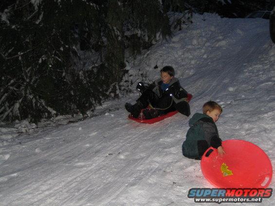 Children sledding down a snowy hill