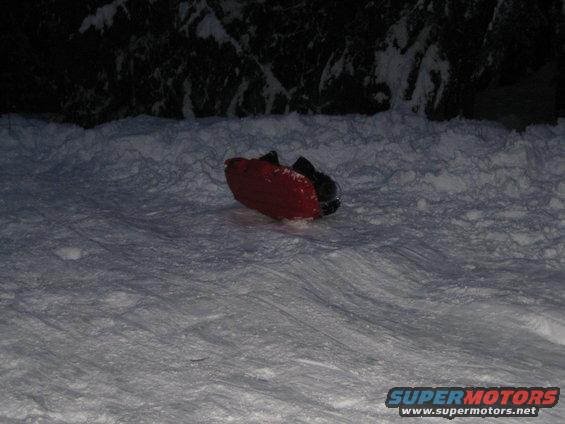 Red plastic sled on snow, with dark handles visible