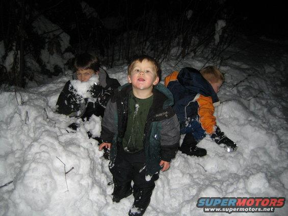 Three children playing in the snow at night