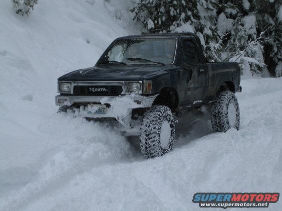 Toyota pickup truck with large tires driving through deep snow