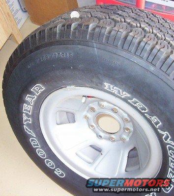 Close-up of a Goodyear Wrangler tire on a silver rim. Tire has text like P265/75R16