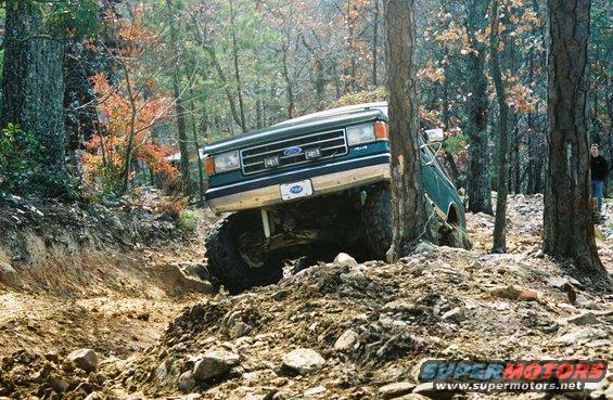 Green 1990 Ford Bronco 4x4 off-roading on a rocky trail