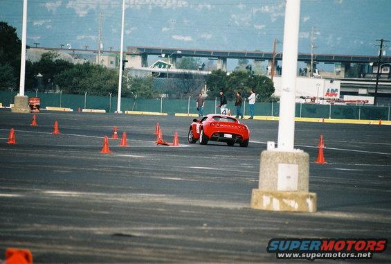 Red sports car on a race track with orange cones