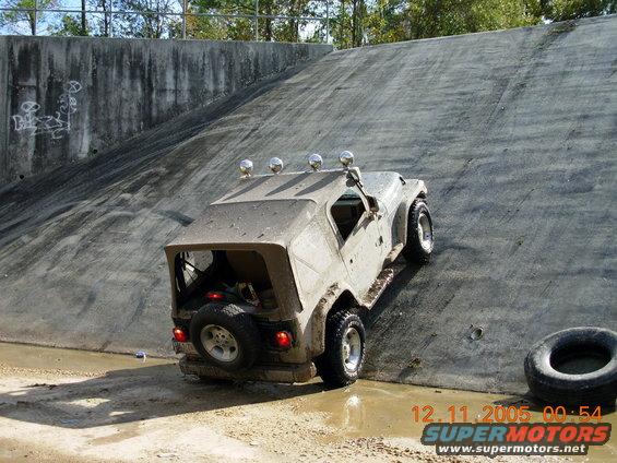 Tan Jeep Wrangler climbing a concrete wall with four lights on the roof