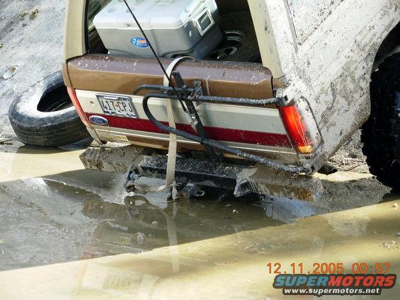 1987 Ford Bronco rear, brown and white, stuck in mud with spare tire and cooler
