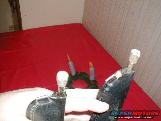 Close-up of two car door handles, one black and one partially visible, with a small wreath and two candles in the background