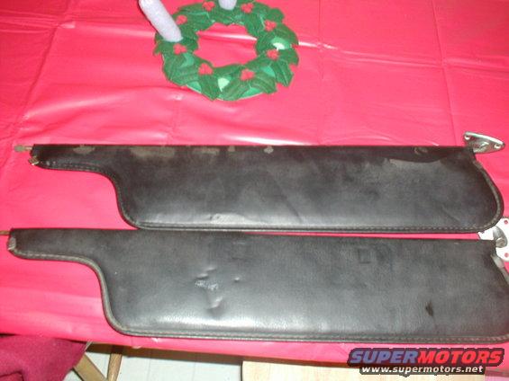 Two black car sun visors on a red surface, with a small wreath above them
