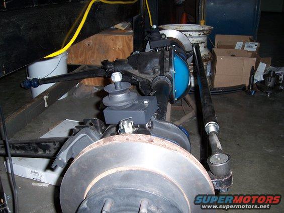 Close-up of vehicle front axle, steering linkage, and brake rotor