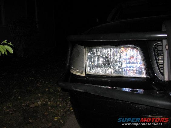 Front corner of a black 2000 Ford Crown Victoria, showing the headlight and part of the grille. Bull bar is visible