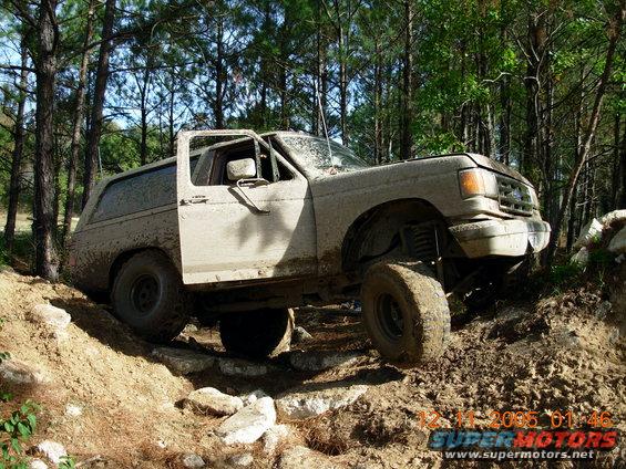 1987 Ford Bronco off-roading, front 3/4 view, covered in mud