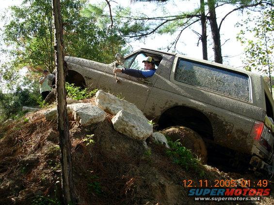 1987 Ford Bronco navigating a steep, rocky, muddy trail