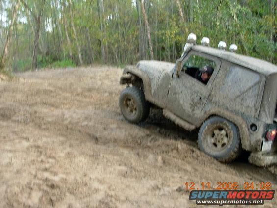 Mud-covered Jeep Wrangler driving off-road