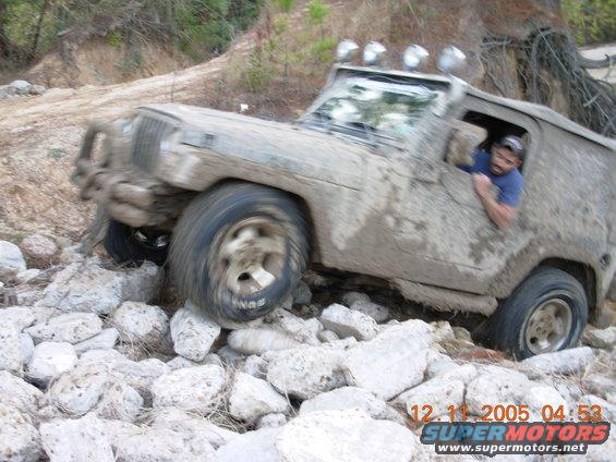 Muddy off-road vehicle navigating rocky terrain