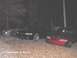 1996 Ford Mustang - Three Ford Mustangs, including a red one in the foreground, are parked outside at night.