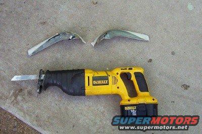 yellow DeWalt reciprocating saw with battery, and two chrome car trim pieces on concrete