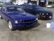 1965 Ford Mustang - Two Mustangs, a blue coupe and a black convertible, are parked side-by-side in a lot.