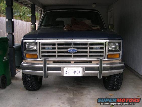 Front view of a blue Ford Bronco with a prominent chrome grille and a license plate reading 461-MQK