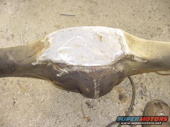 Differential housing with a welded patch on top, resting on a concrete surface