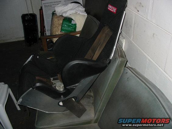 Racing seat on top of a car seat, with a safety instructions poster in the background