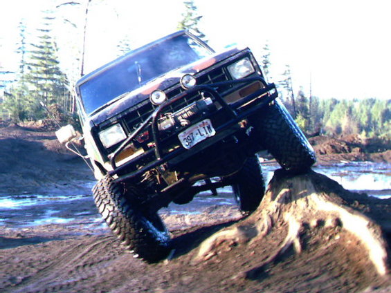 1987 Ford Bronco II climbing dirt mound with winch and brush guard