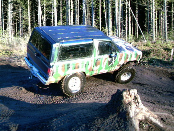1987 Ford Bronco II with camouflage paint, lifted suspension, and off-road tires on a dirt track