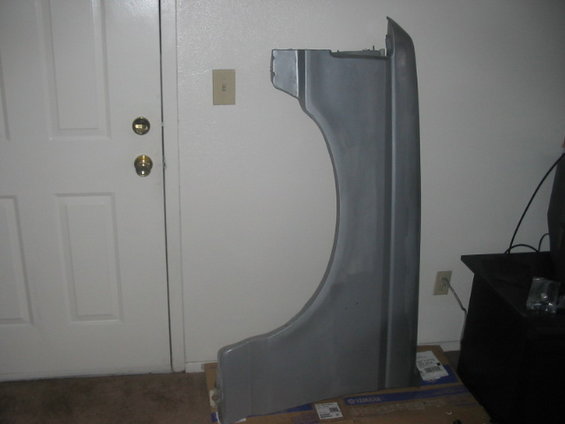 Gray car fender leaning against a wall