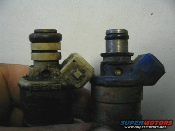 Two dirty fuel injectors, one with a yellow connector and one with a blue connector