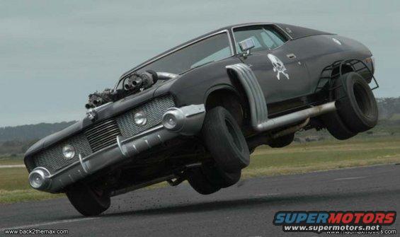 Black customized car on two wheels, with exposed engine, side pipes, and skull decal