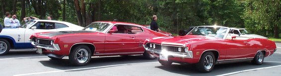 1970 Ford Torino GT coupe and convertible parked next to a white and blue muscle car
