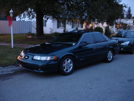 1995 Ford Taurus sedan parked on street, another dark car behind it