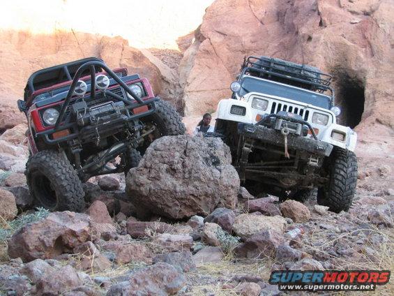 Red 1990 Suzuki Samurai and white Jeep Wrangler off-roading over large rocks