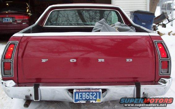 Red Ford Ranchero from behind, parked in snow. Another red car is visible in the background