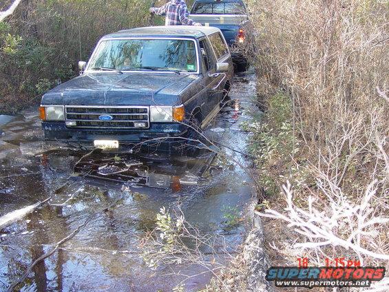Ford Bronco stuck in water with another truck behind it