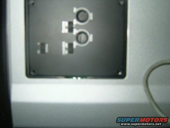 Dashboard panel with four buttons and two circular dials, silver trim, and a coiled cable