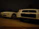 1993 Ford Probe - Two white cars, a Ford Probe and a Subaru WRX, are parked together at night.