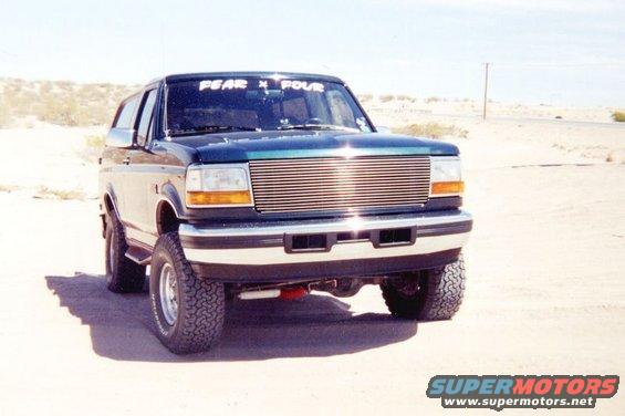 1995 Ford Bronco front view, dark green with chrome grille and off-road tires
