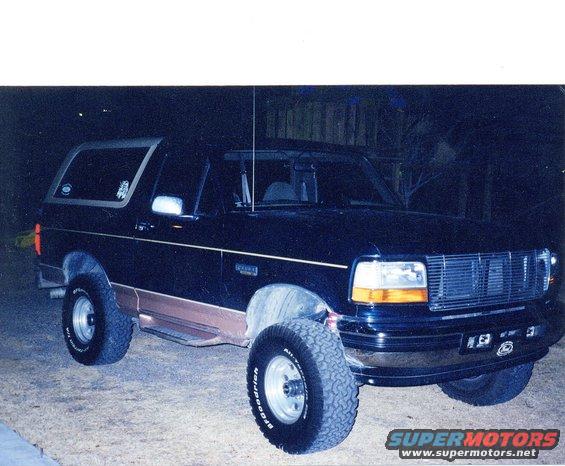 1995 Ford Bronco, dark blue with tan lower trim, parked outdoors at night