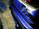 1993 Ford Probe - Close-up of a blue car's fender and open trunk area, revealing internal components.