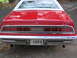 1976 Ford Thunderbird - The rear of a red 1976 Ford Thunderbird with a white roof and a chrome bumper is visible.
